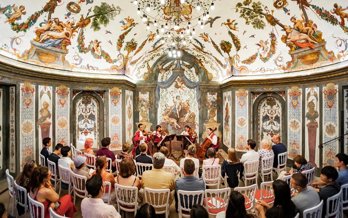 Seated concert audience beneath painted ceilings in Sala Terrena